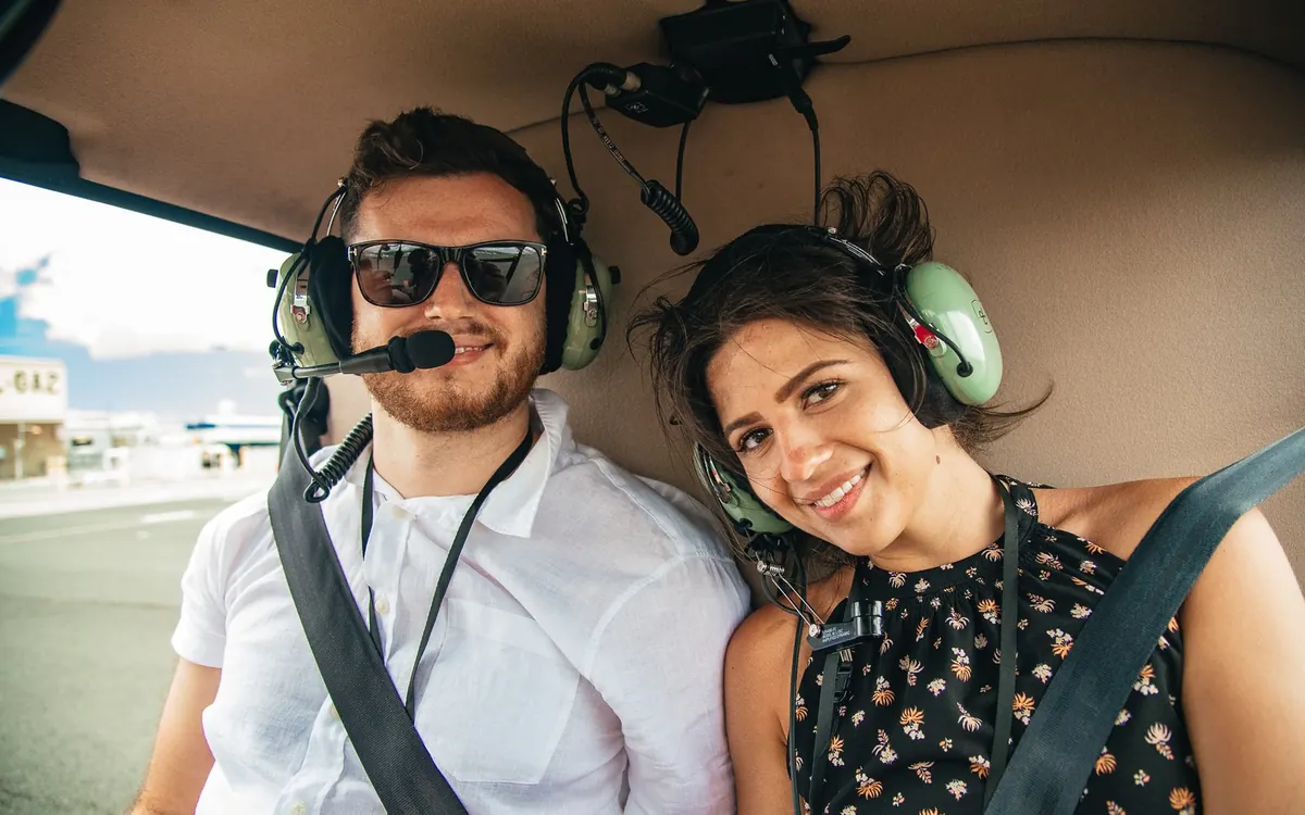 Two passengers in a helicopter over the Oahu coastline
