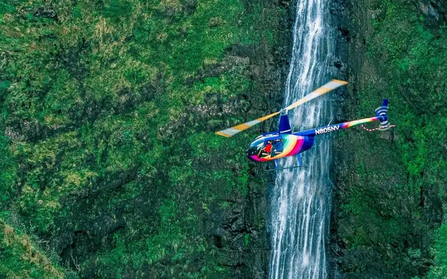 Passengers in a doors-off helicopter above the Oahu coastline